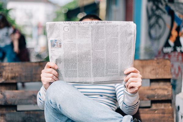 Person reading with newspaper in front of face.