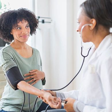 African American doctor taking pregnant womans blood pressure