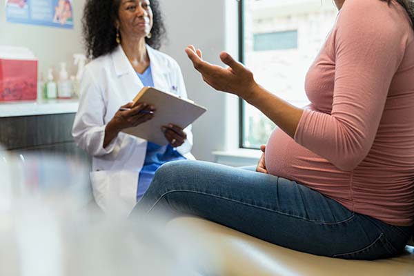 Pregnant woman gestures while talking to obstetrician