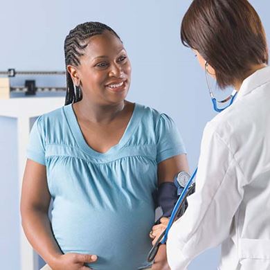 Women Doctor taking pregnant African women's blood pressure