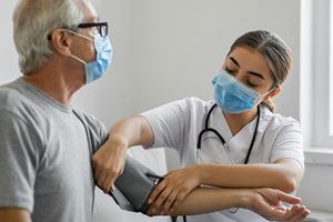 A female home healthcare worker checks a man's blood pressure.