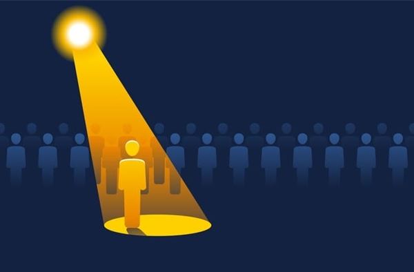 Decorative image of a spotlight shining on one person while others are lined up in the background