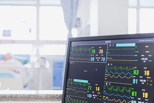 heart rate monitor, patient and doctors in background in emergency room