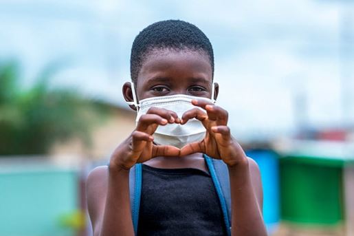 Girl in face mask making heart sign.