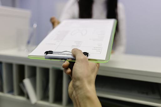 handing over clipboard to office worker