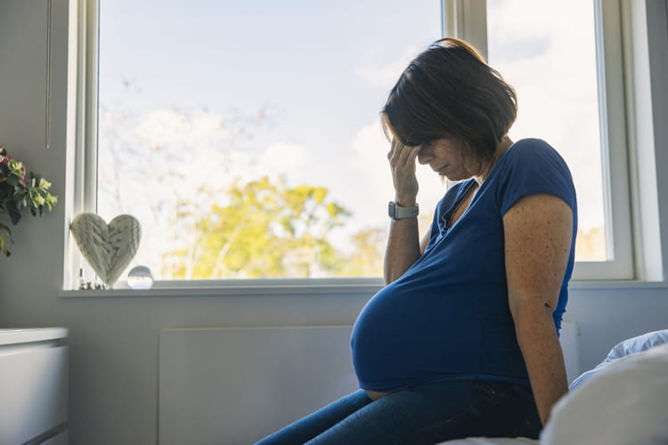 mature pregnant woman sitting on bed
