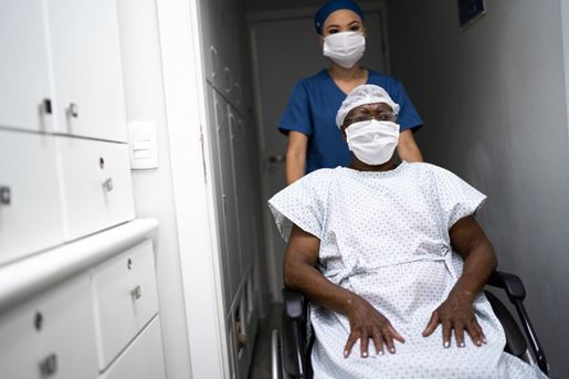 senior female patient in a wheelchair being pushed by a nurse in a hospital.