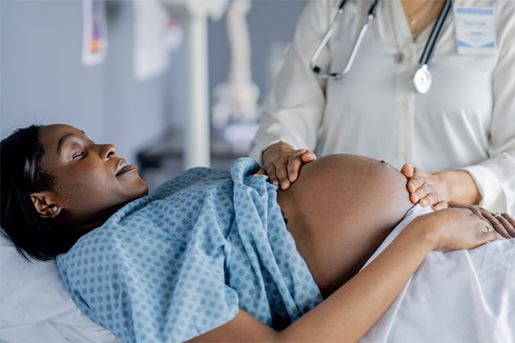pregnant woman lays on exam table during prenatal appointment