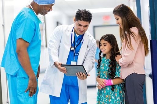 surgeons talking to a pediatric patient and her mother in hospital hallway