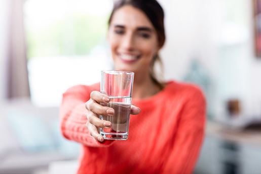 young woman showing drinking glass with water